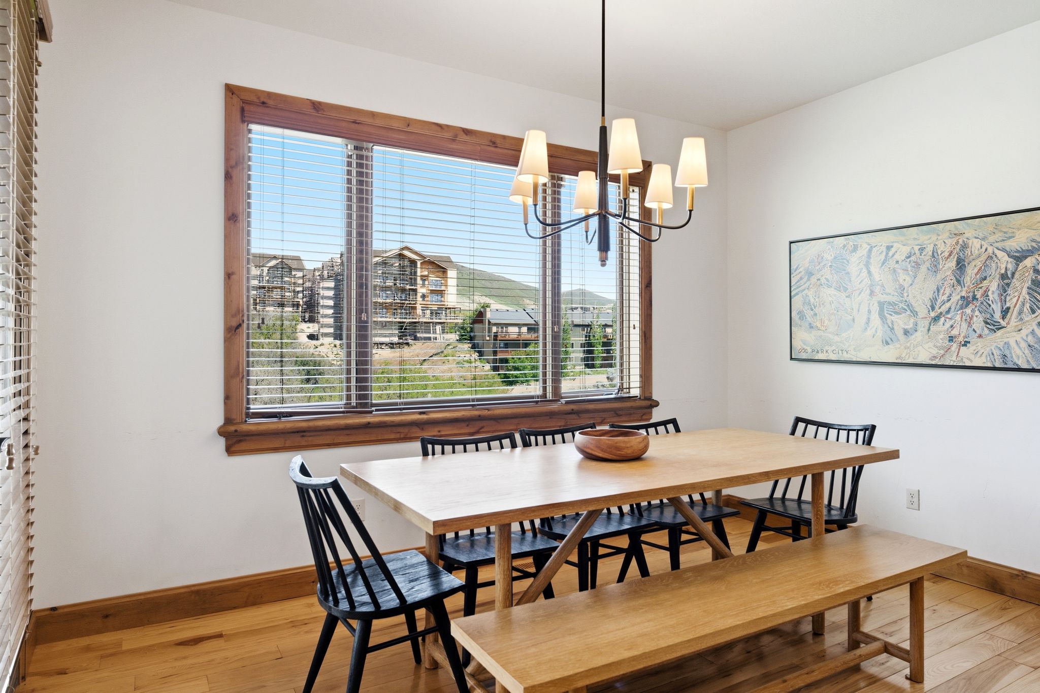 Dining area featuring a large window with wood trim, wood-finish flooring, and a multi-arm chandelier