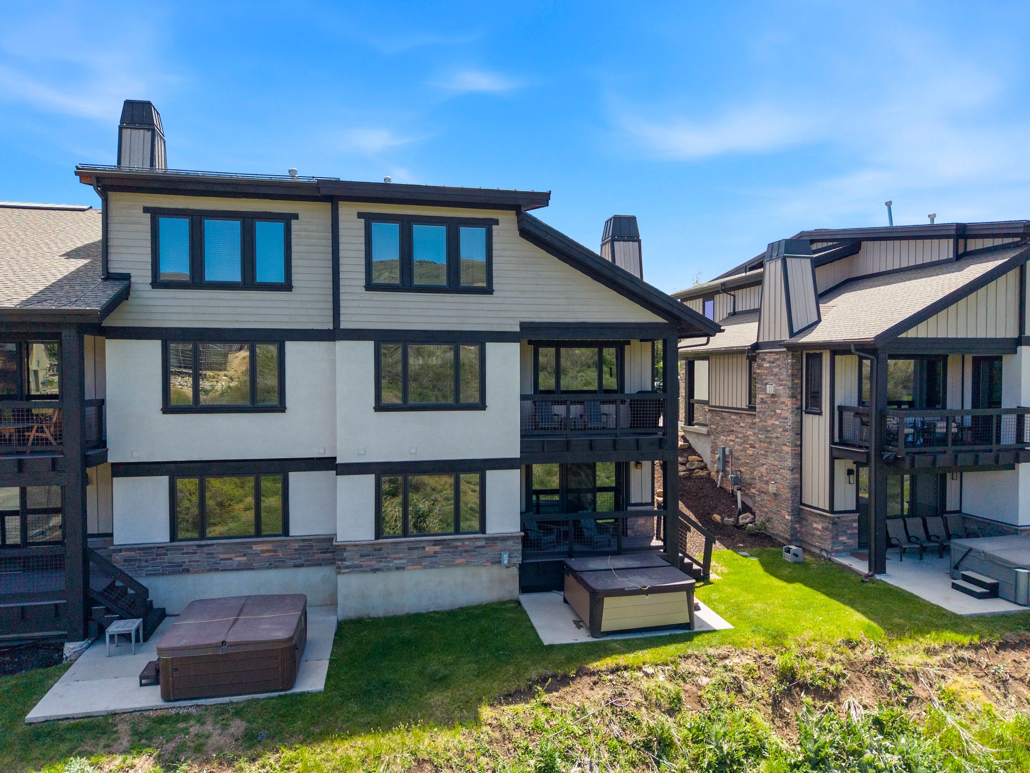 Multi-level exterior featuring light-colored siding with dark trim, stone veneer accents, and multiple private balconies