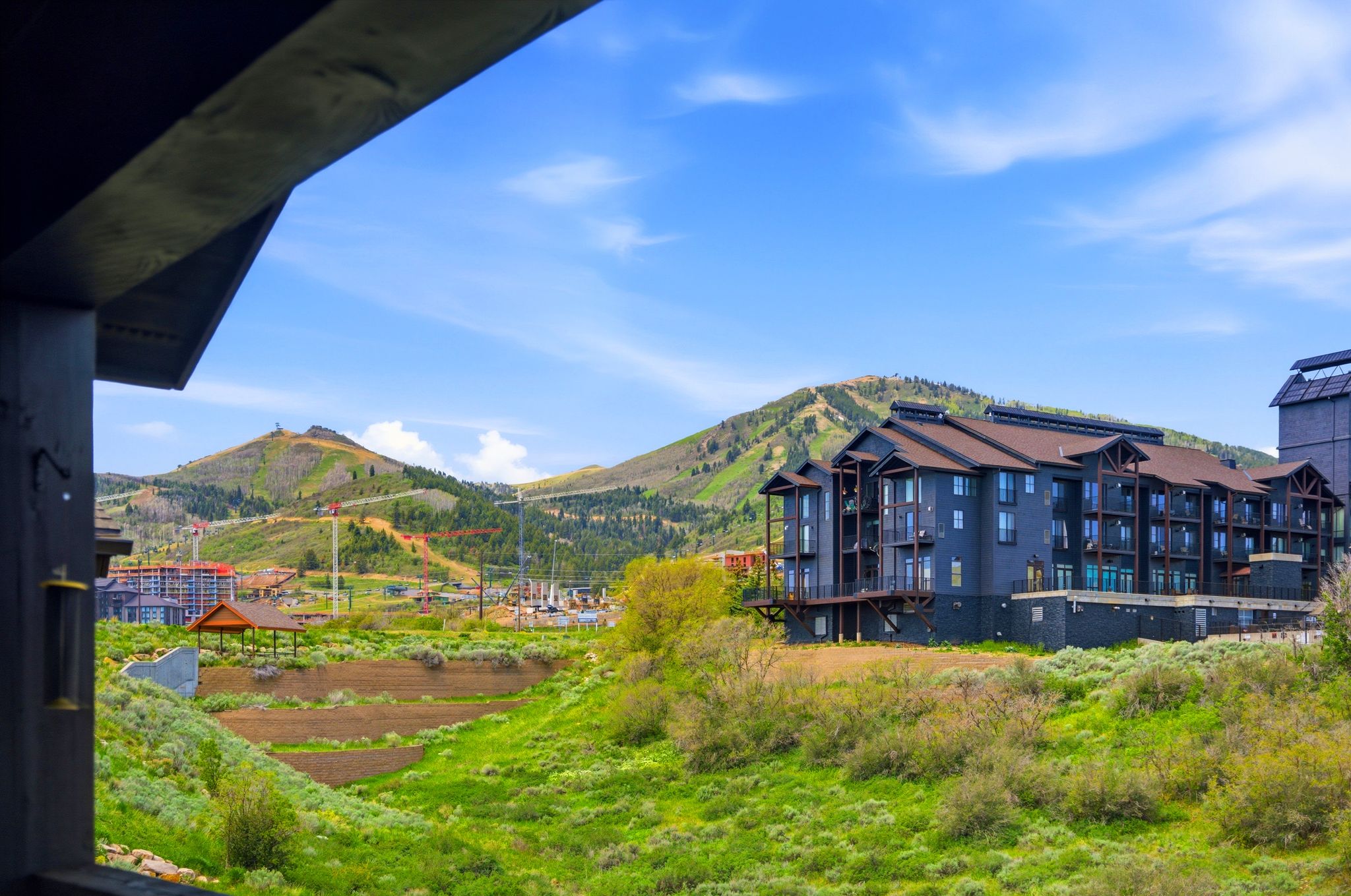 Mountain landscape with a dark-toned residential building featuring multiple balconies and a brown roof