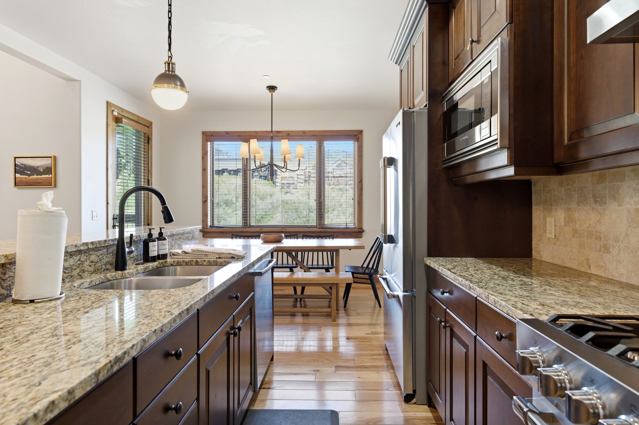 Kitchen featuring granite countertops, dark wood cabinetry, stainless steel appliances, and a double basin sink with a gooseneck faucet