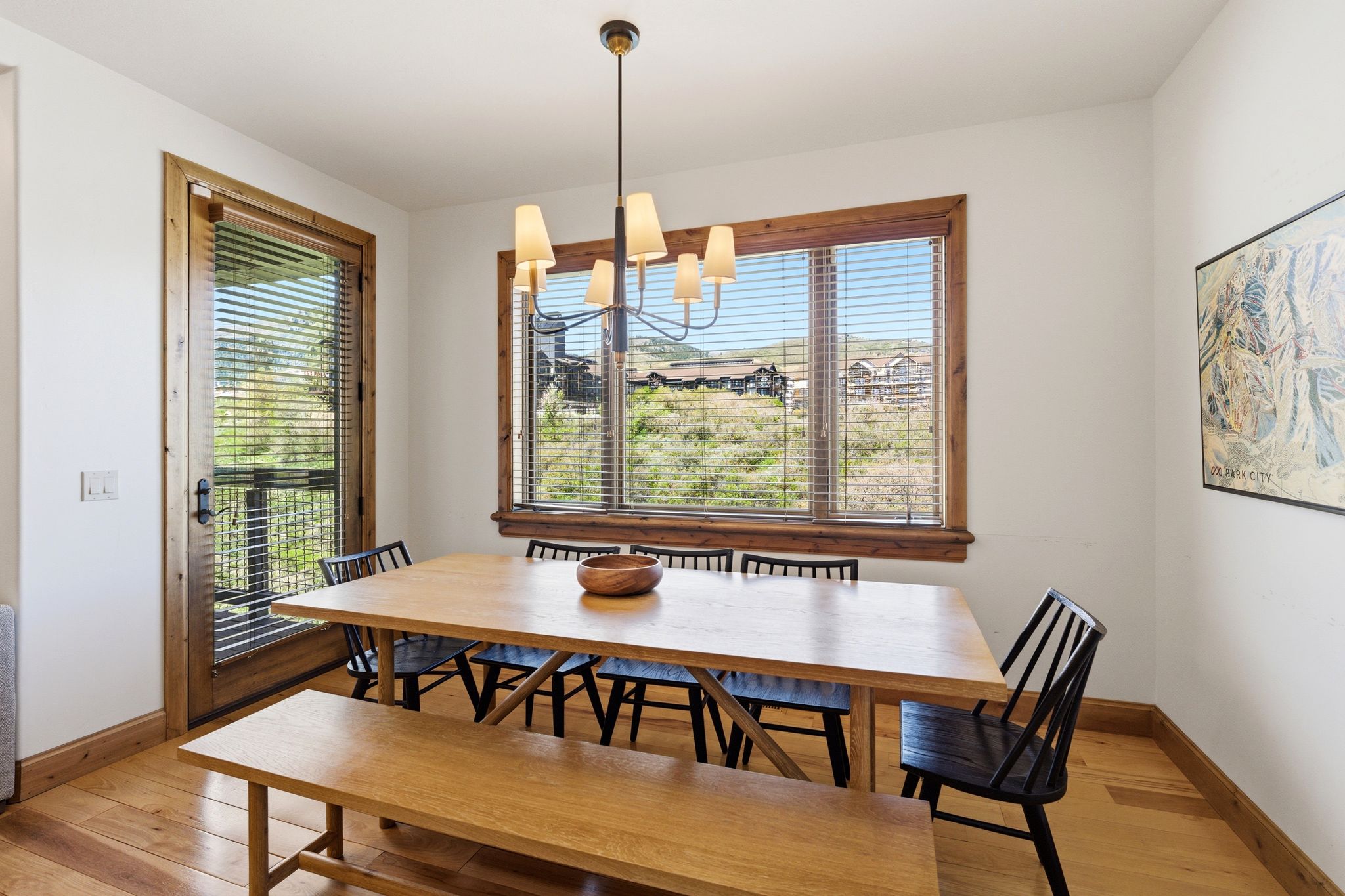 Dining area with light wood-finish flooring, white walls, and wood trim detailing around windows and exterior door