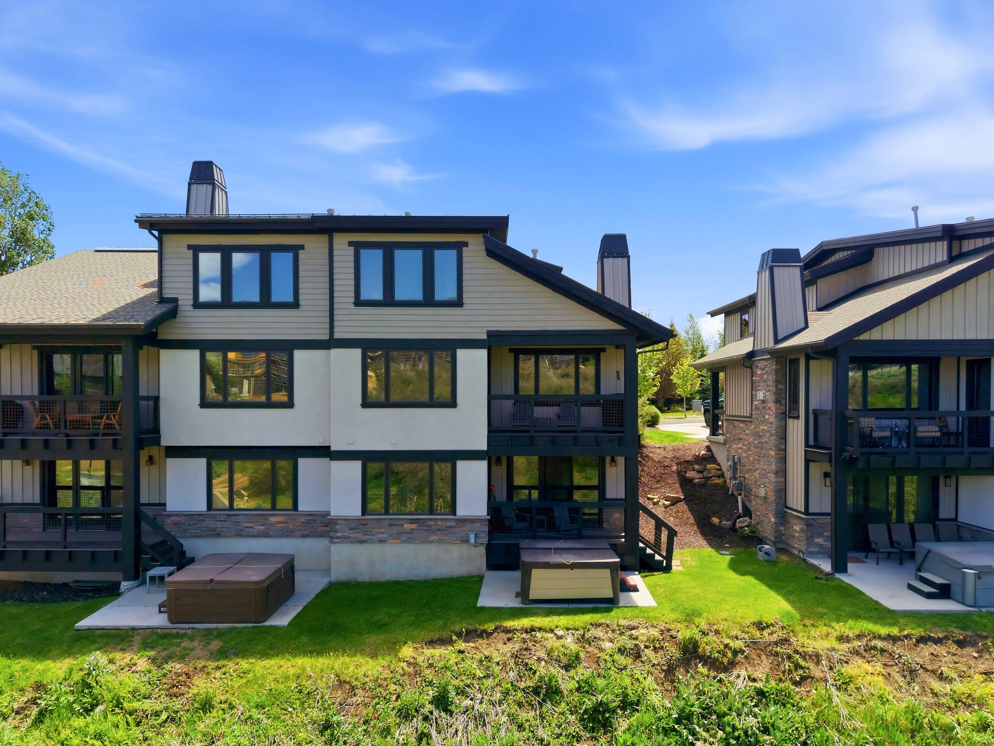 Multi-level residential exterior featuring warm beige siding and stone accents