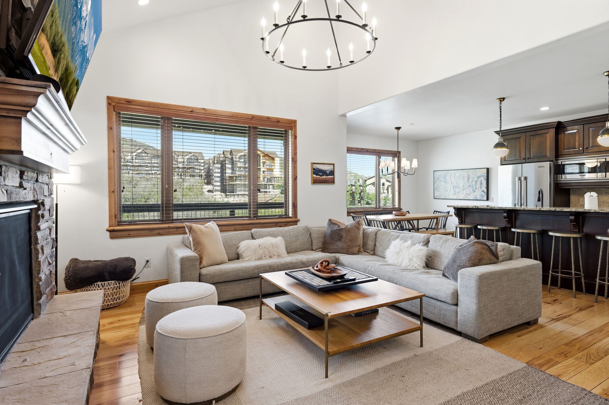 Living space with vaulted ceilings, a stone fireplace, and wood-finish flooring