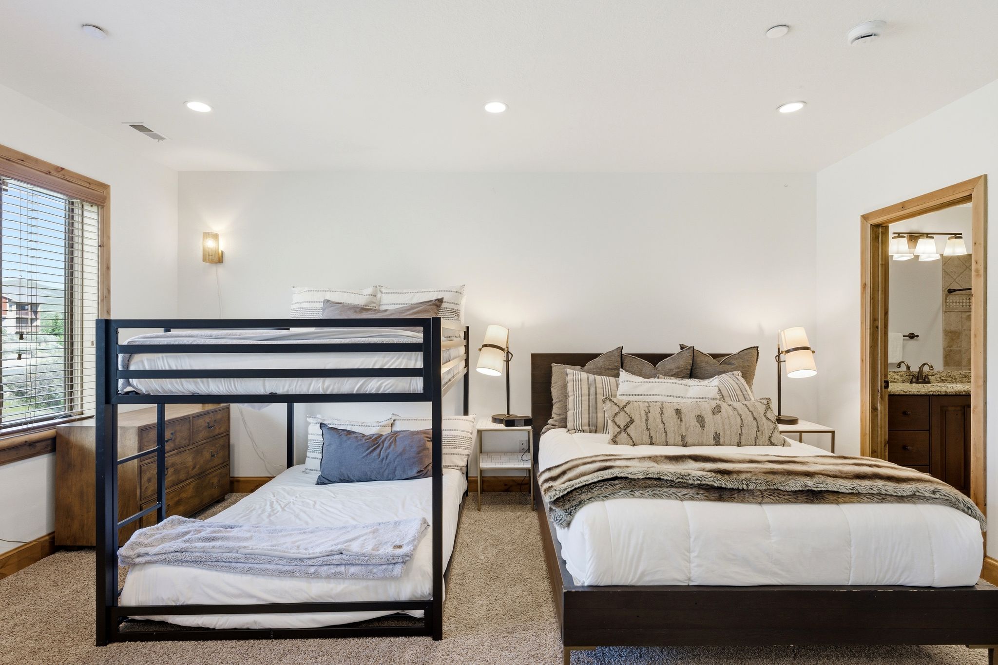 Carpeted bedroom featuring a bunk bed, a queen-sized bed, recessed lighting, and a window with wood trim