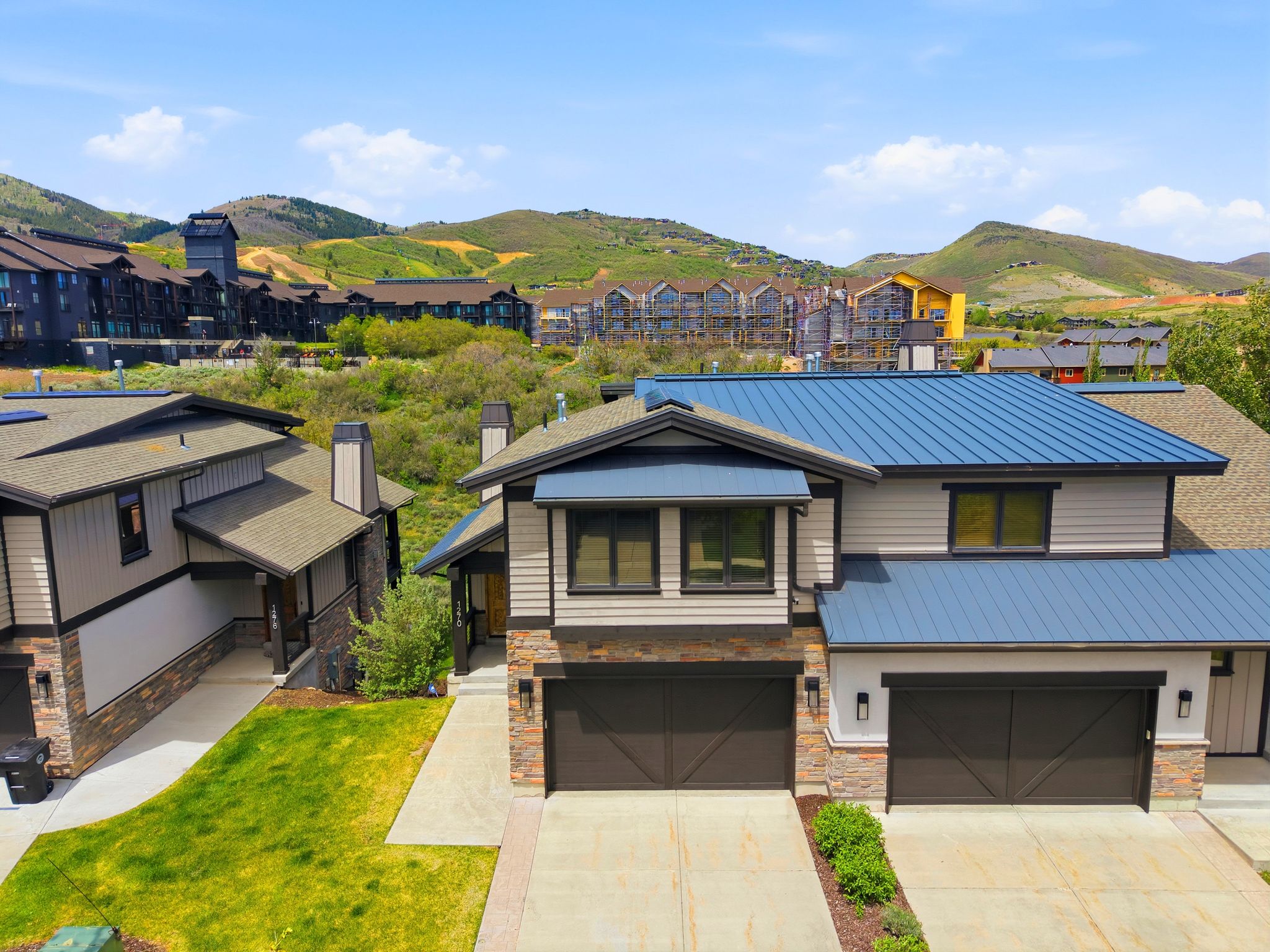 Modern exterior featuring a prominent blue metal roof and stone veneer accents