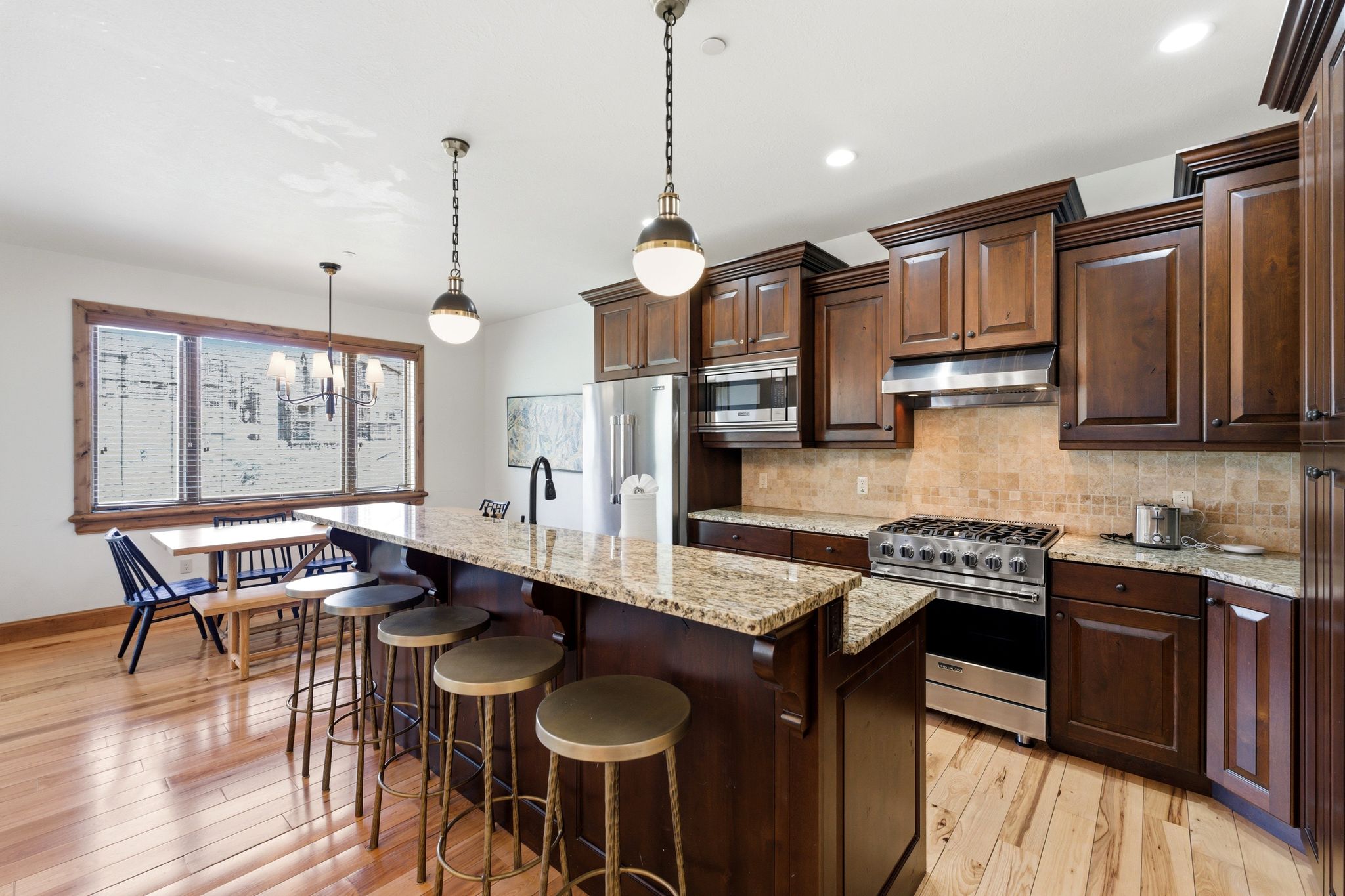Kitchen featuring wood-finish flooring, dark wood cabinetry, and granite countertops