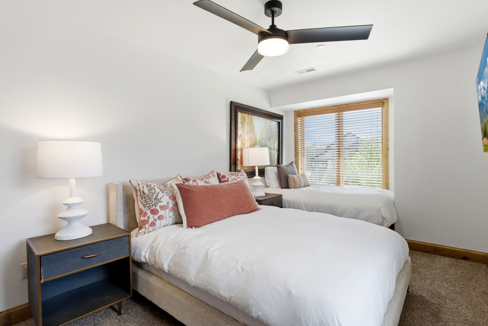 Bright room featuring two beds and a window with wood trim