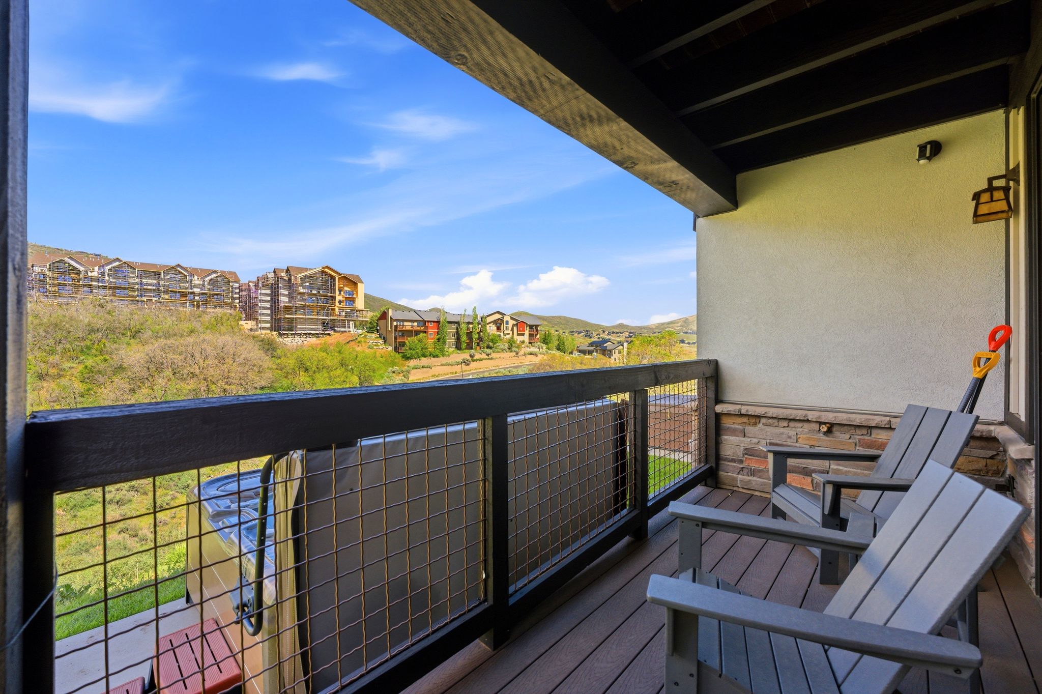 Balcony featuring composite decking, a wire mesh railing, and a stone veneer wall accent