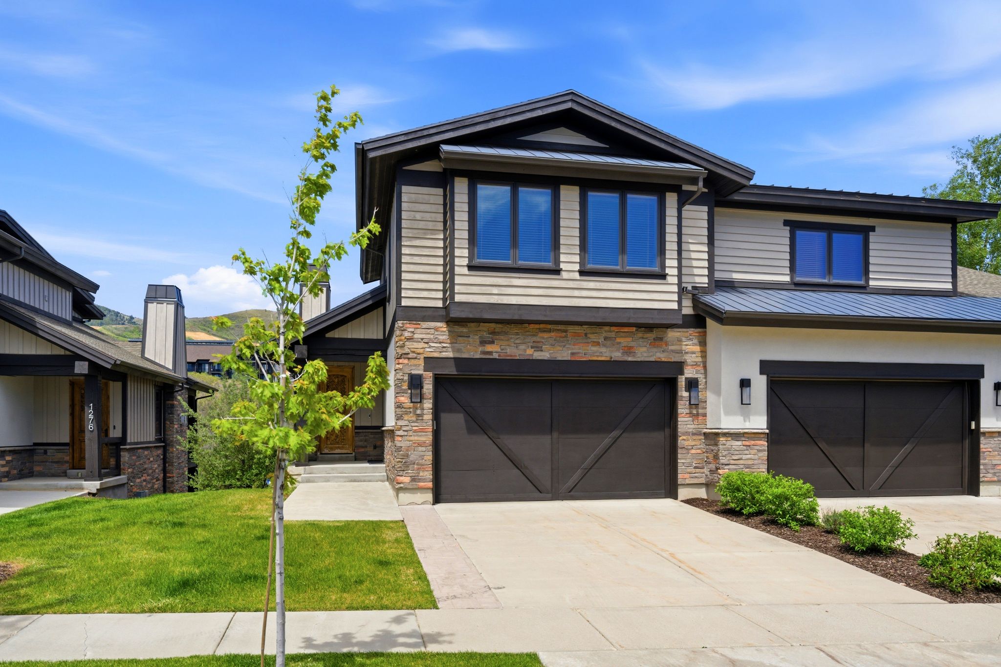 Contemporary facade featuring stacked stone accents, horizontal siding, and dark trim