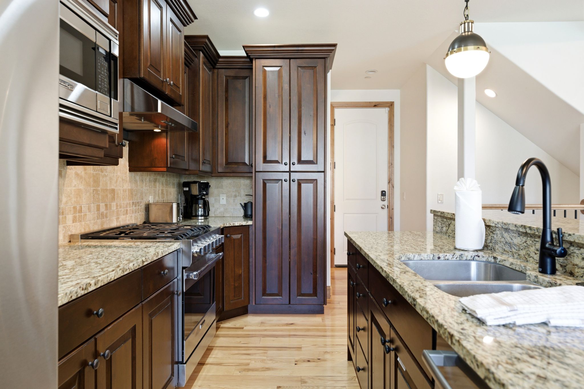 Kitchen featuring wood-finish flooring, dark wood cabinetry, and speckled granite countertops