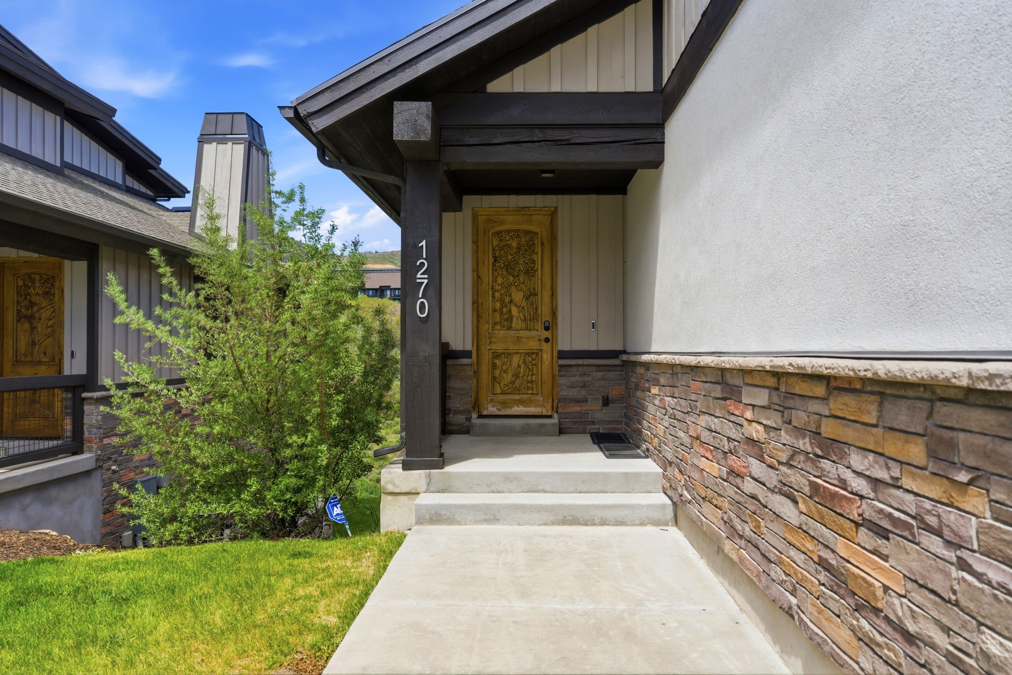 Carved wooden entry door framed by a dark timber-framed porch with white house numbers