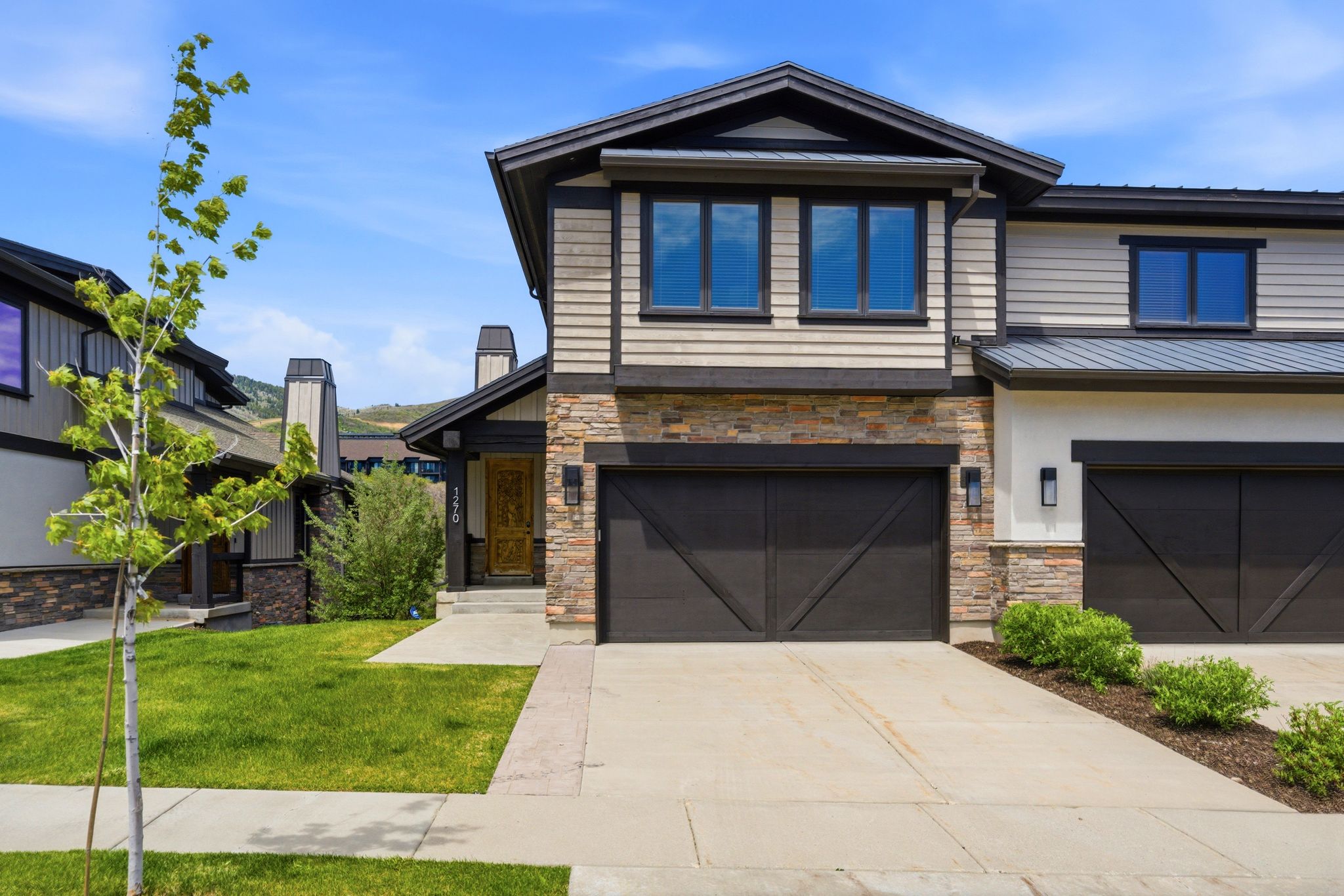 Contemporary exterior featuring wood-look siding, stone accents, and dark trim