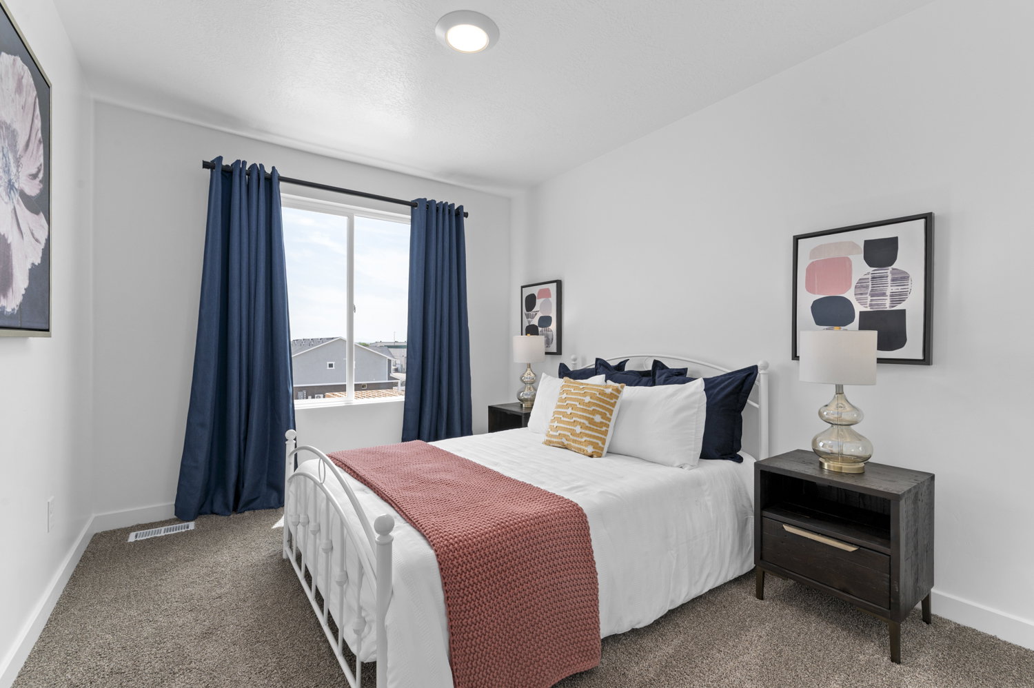 Spacious bedroom featuring neutral carpeting, a large window with ample natural light, bright white walls, a flush-mount ceiling light, and white baseboards