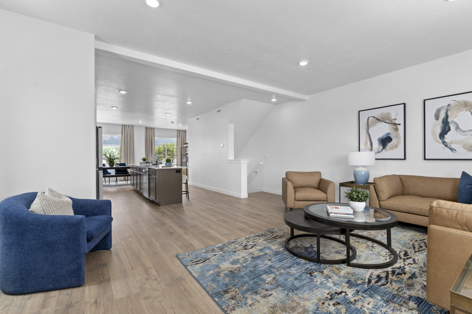 Open-concept living space featuring wood-finish flooring, recessed lighting, white walls, and a staircase with a white railing