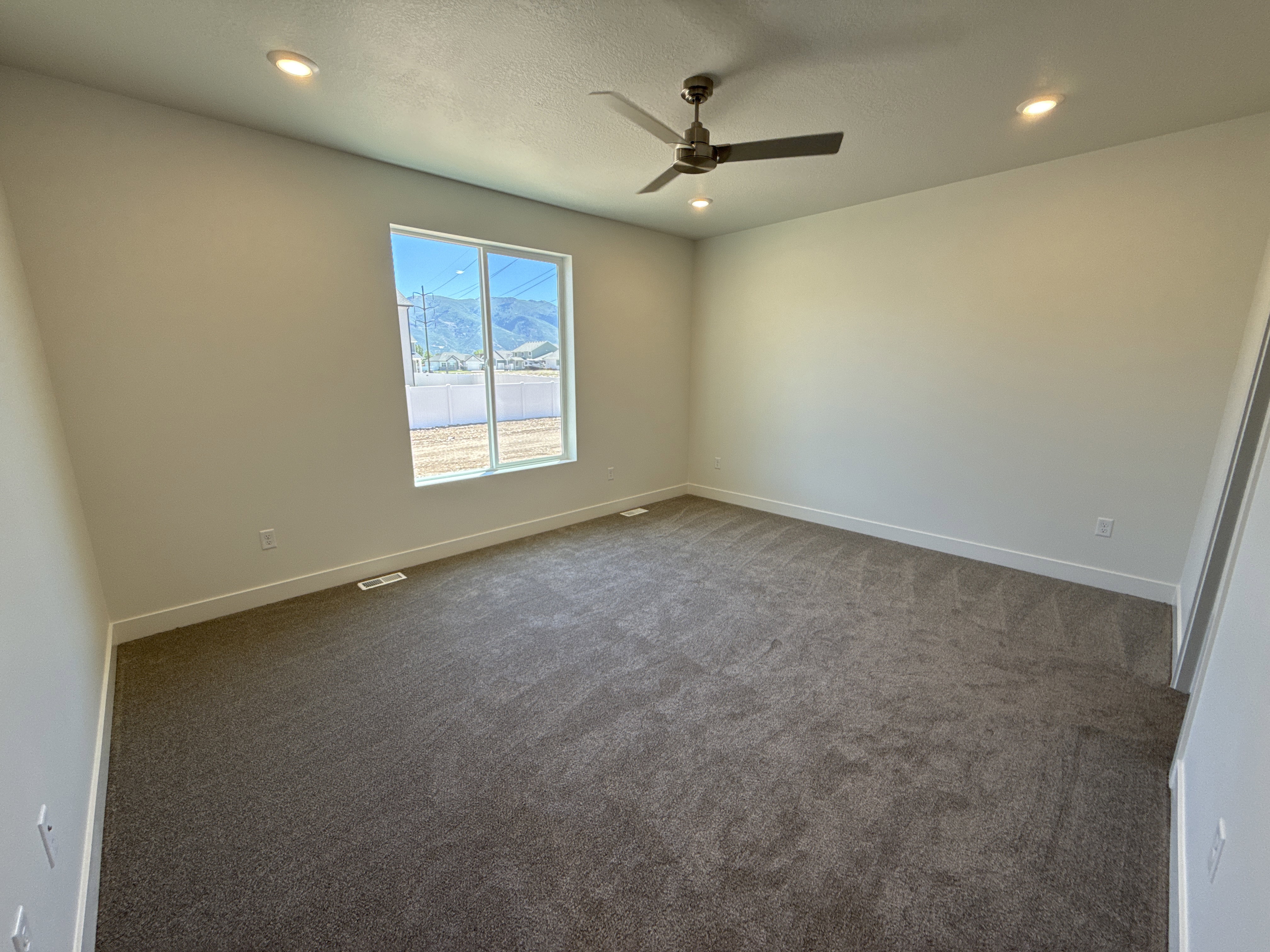 Carpeted interior space featuring a large window, recessed lighting, and a ceiling fan