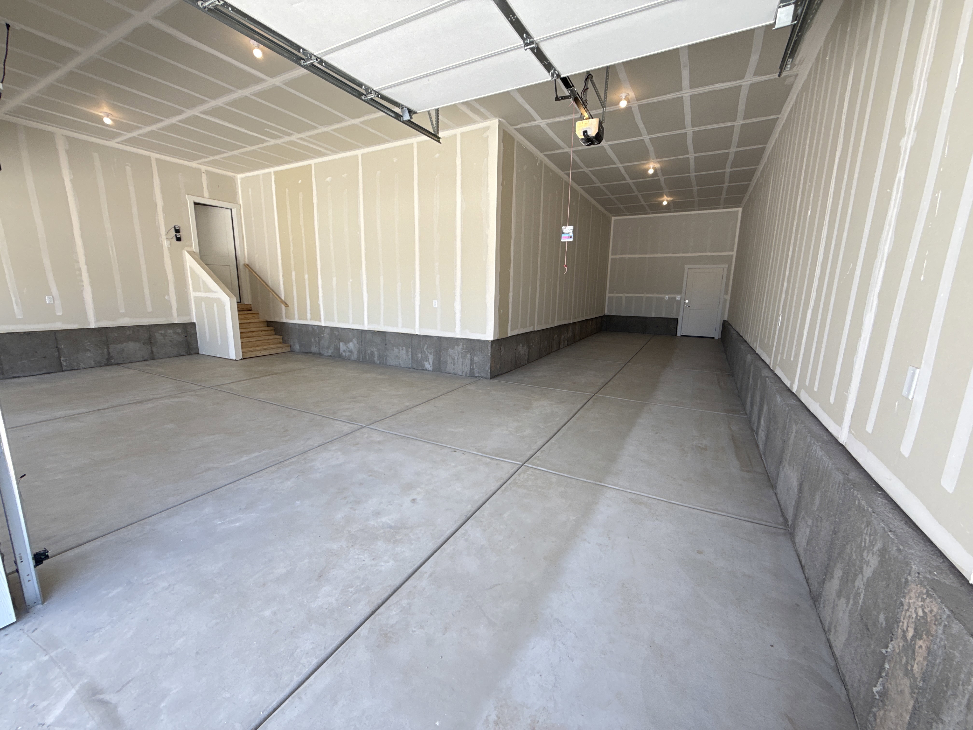 Spacious garage featuring a concrete floor, exposed drywall with taped seams, and recessed ceiling lighting