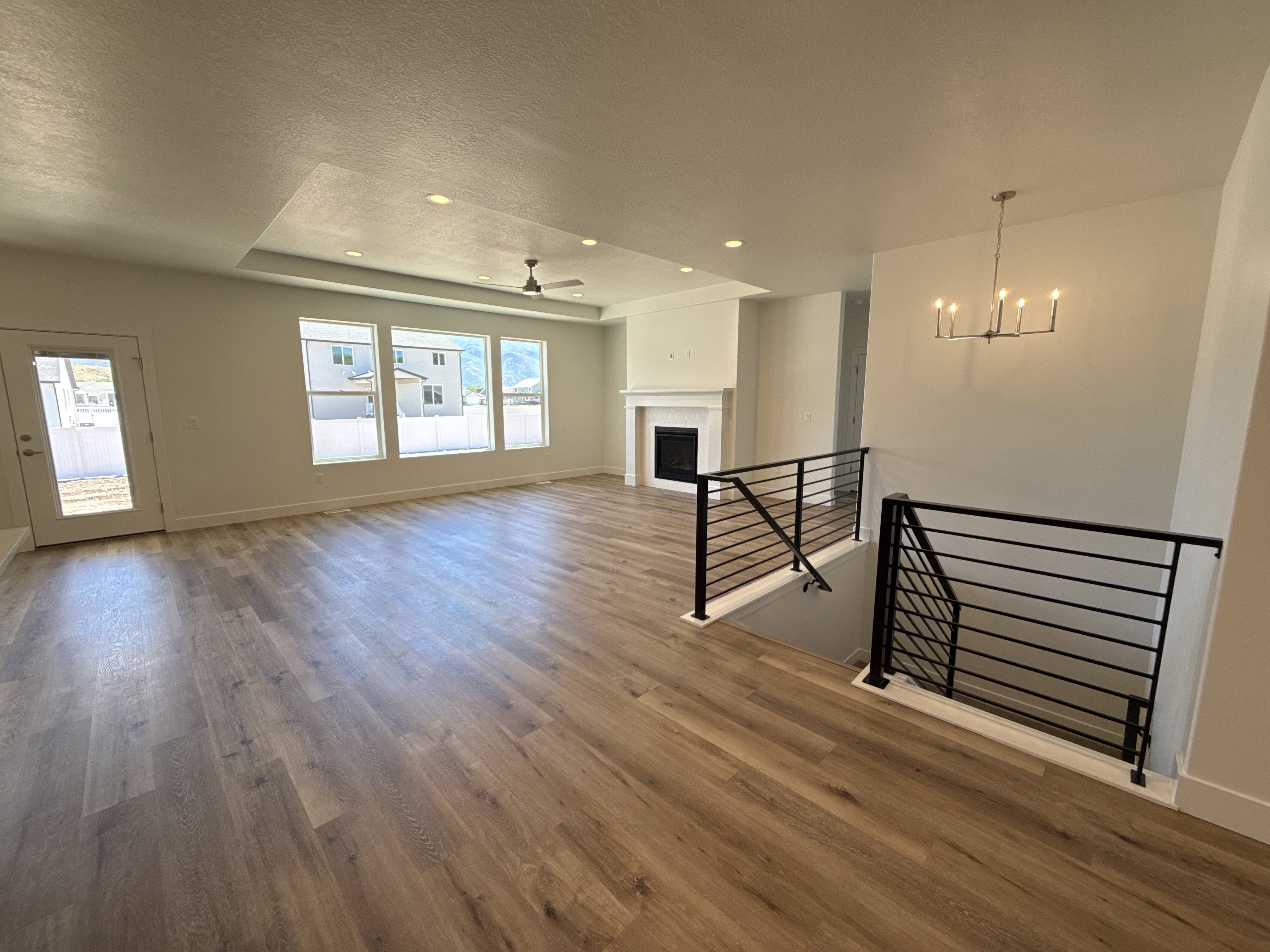 Spacious interior featuring wood-finish flooring, a contemporary fireplace with a white mantel, and a tray ceiling with recessed lighting