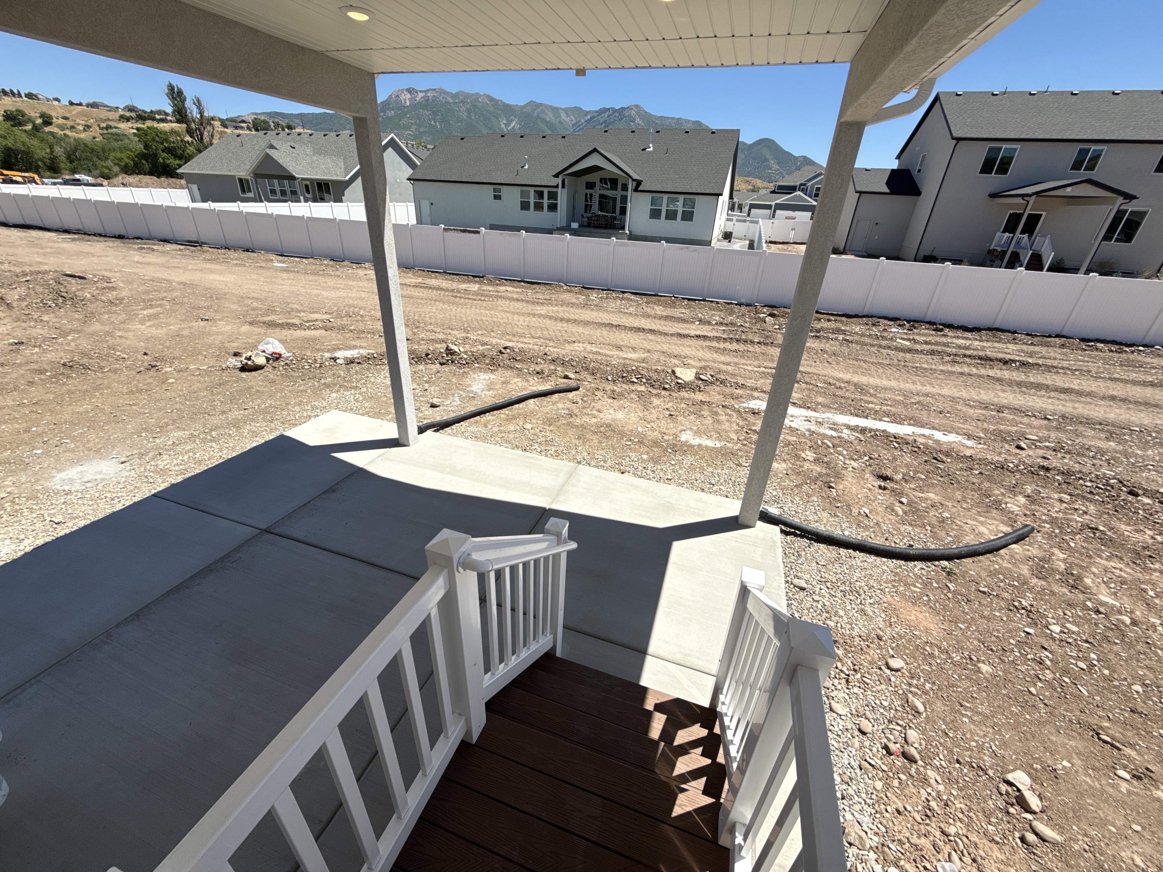 Covered concrete patio with white railing