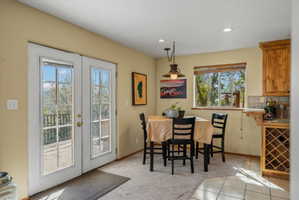 French doors opening to an outdoor area, recessed lighting, wood-finish cabinetry, tile flooring, and a built-in wine rack