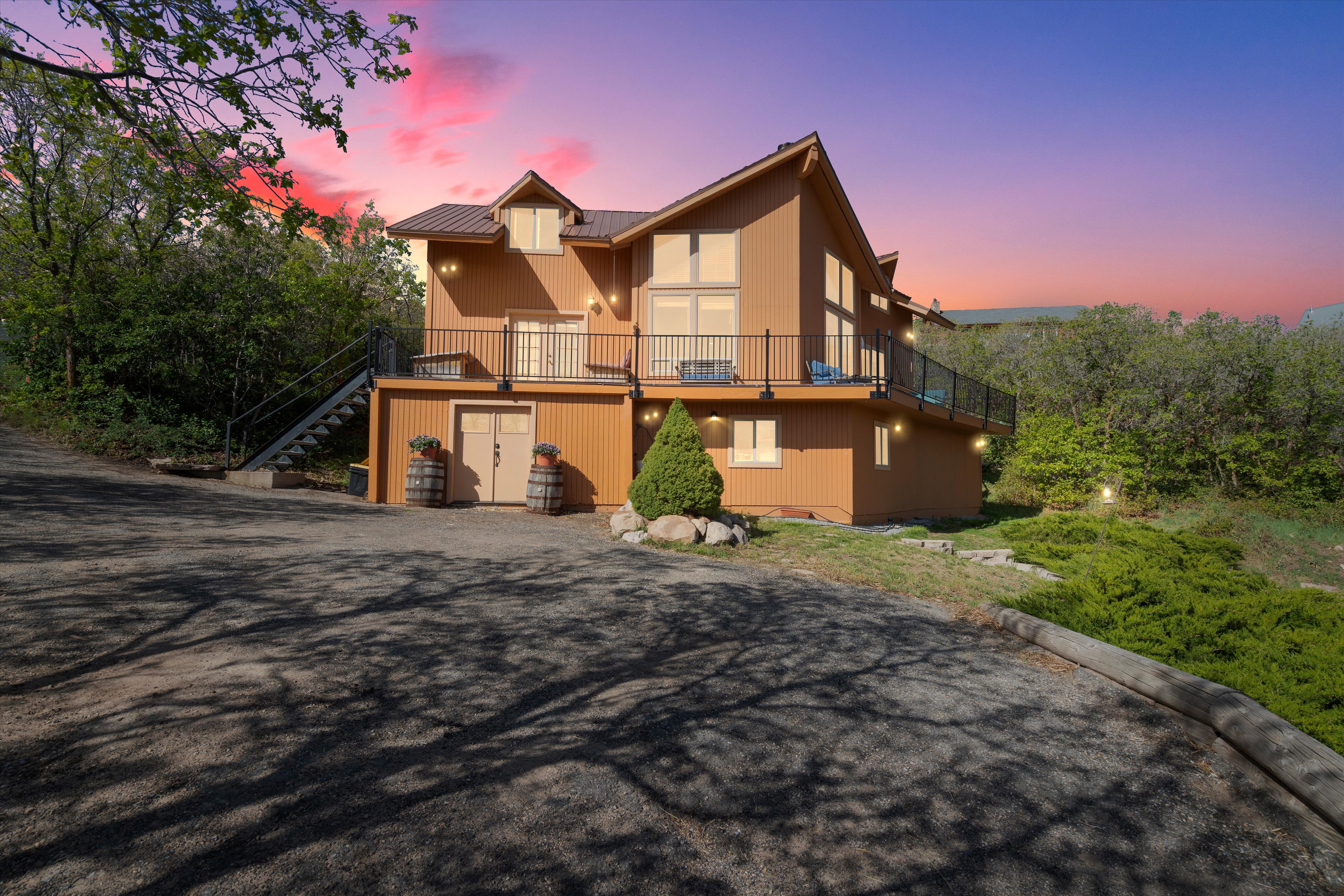 Multi-level property featuring a warm-toned exterior, a metal roof, and a wrap around balcony with black fascia mounted railing