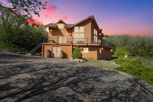 Multi-level property featuring a warm-toned exterior, a metal roof, and a wrap around balcony with black fascia mounted railing