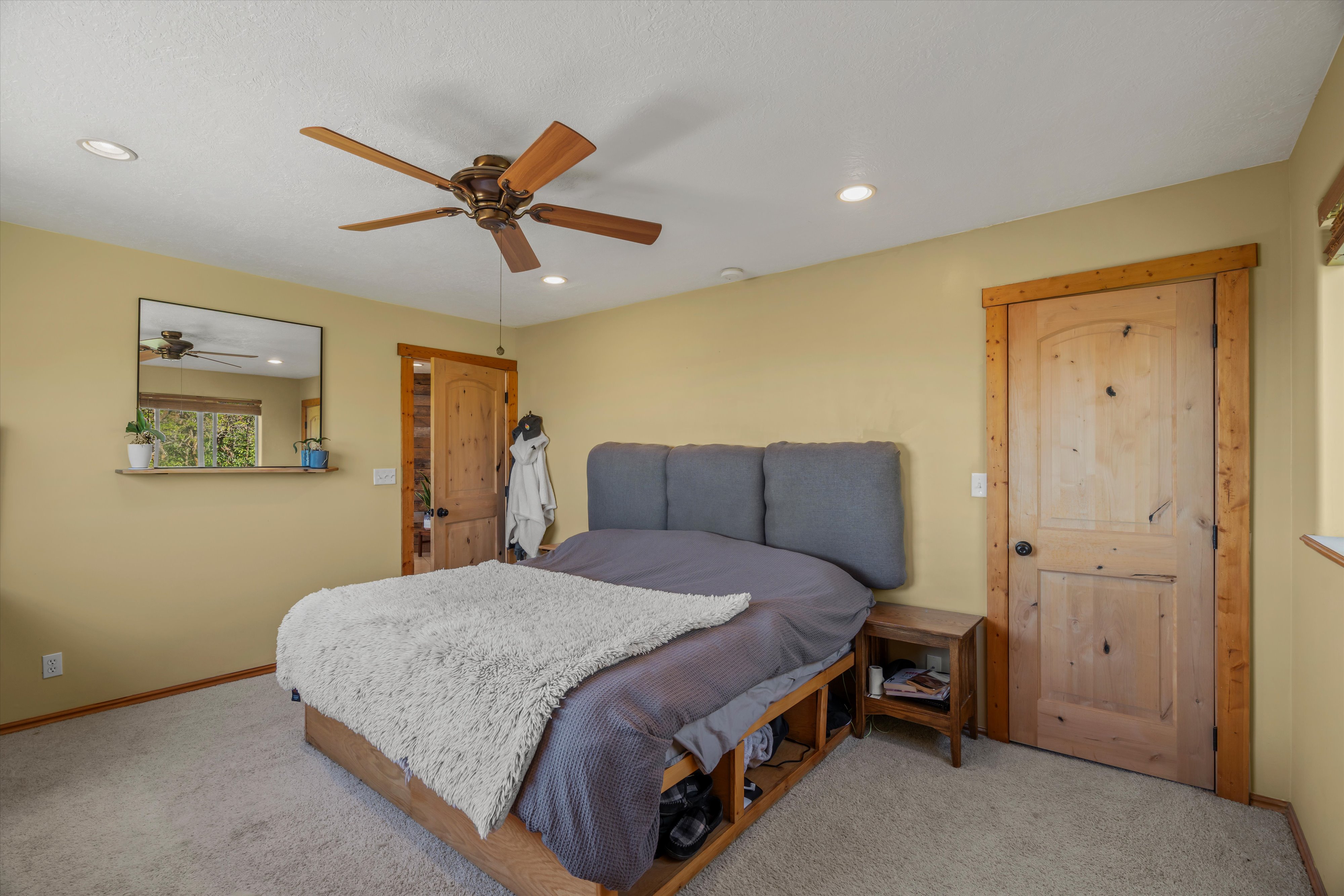 Carpeted room featuring a wood-finish ceiling fan with integrated lighting, recessed ceiling lights, and light wood doors with matching trim
