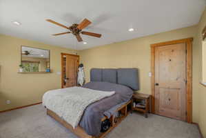 Carpeted room featuring a wood-finish ceiling fan with integrated lighting, recessed ceiling lights, and light wood doors with matching trim