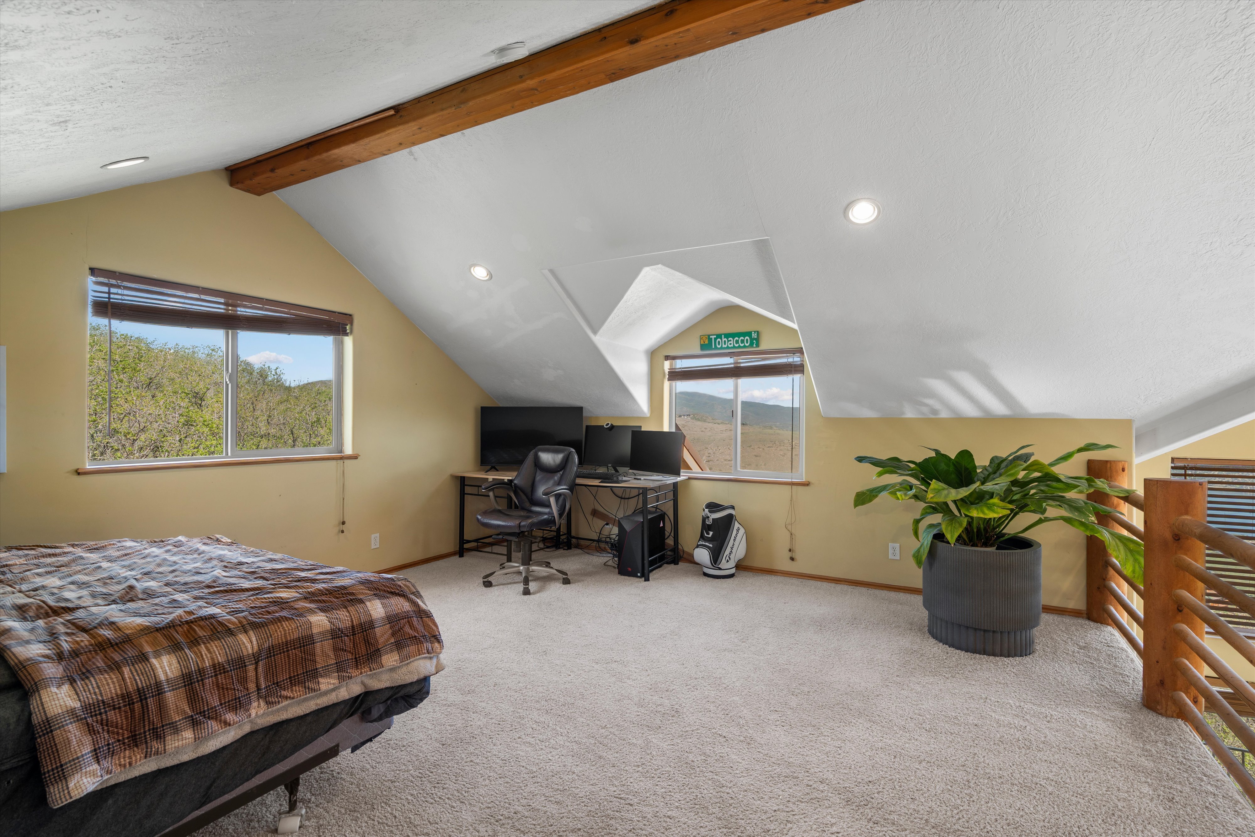 Carpeted loft space featuring exposed wood ceiling beams, sloped ceilings, recessed lighting, and wood railing