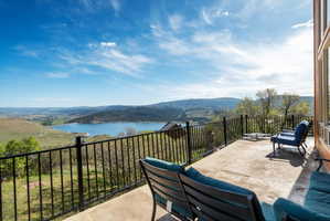 Wrap around patio featuring a black metal railing and expansive water and mountain scenery