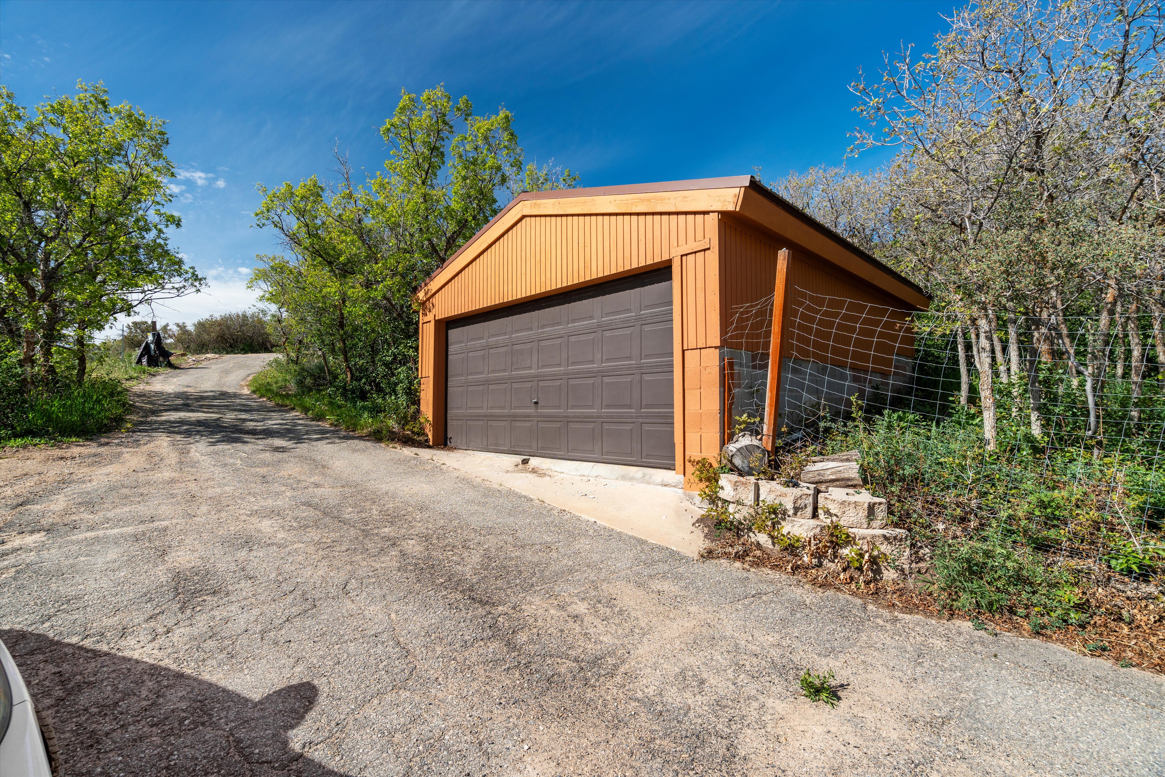 Freestanding detached garage featuring a brown paneled garage door and orange vertical siding