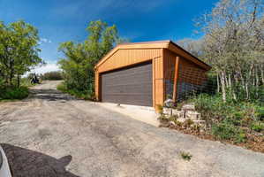 Freestanding detached garage featuring a brown paneled garage door and orange vertical siding