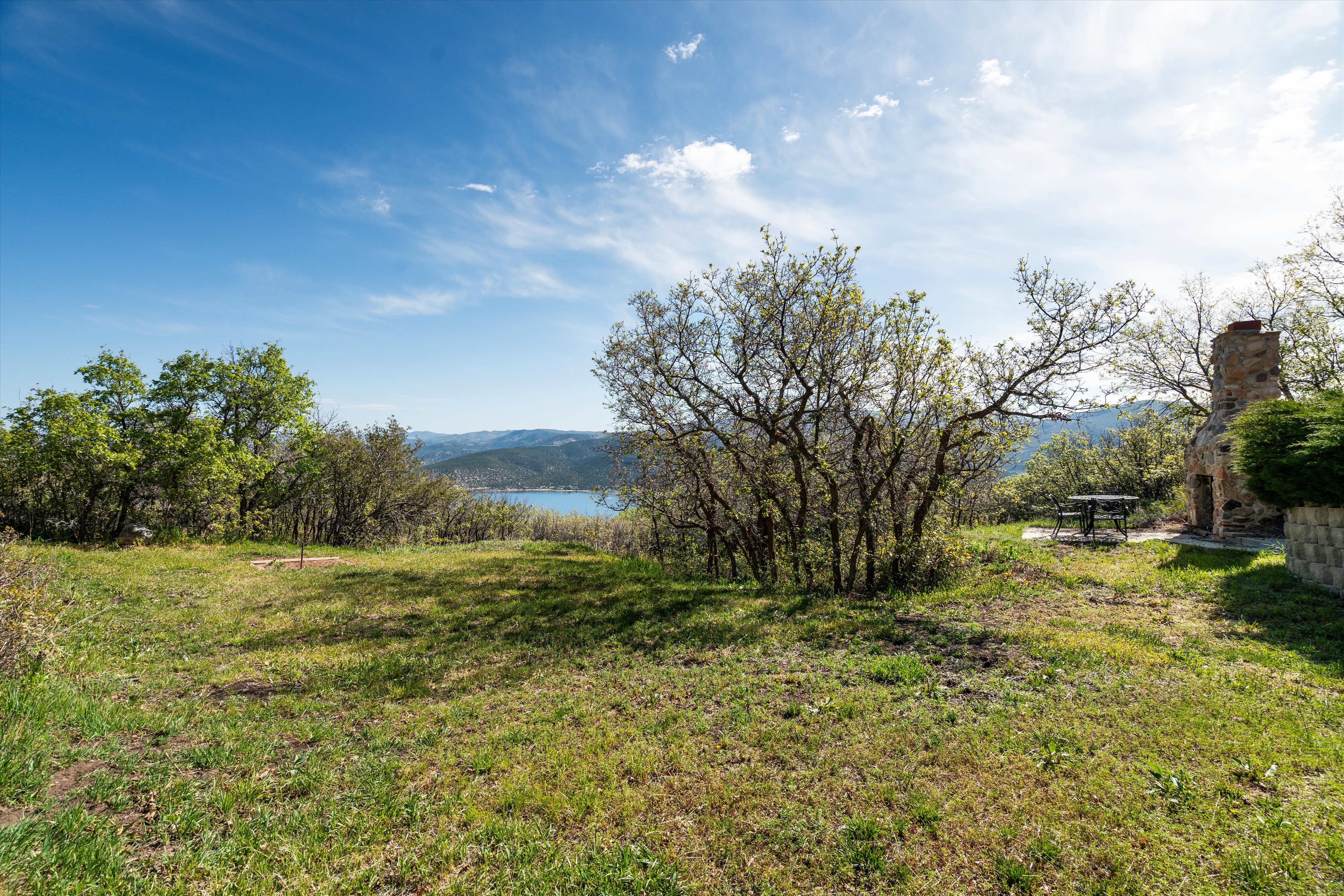 Expansive outdoor space featuring a stone fireplace, mature trees, horseshoe pit, and natural landscaping