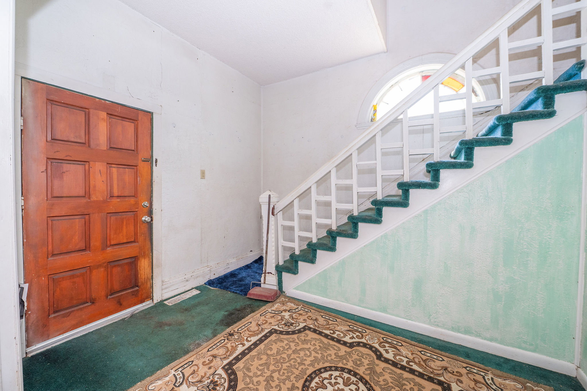 Entryway featuring a paneled wood door, white painted balusters, and a half-round window