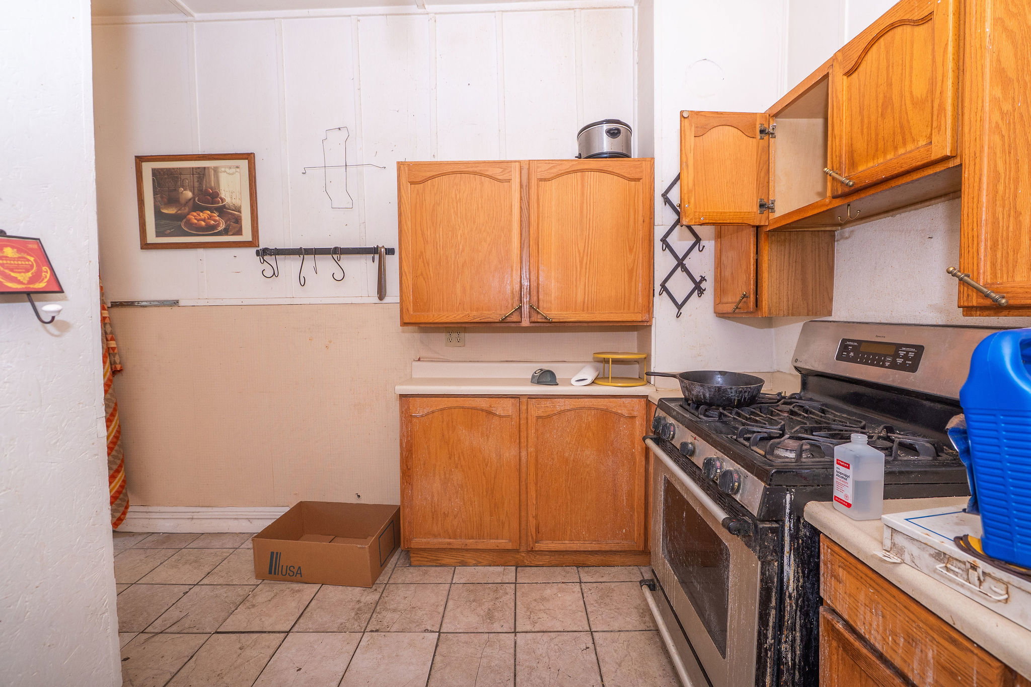 Kitchen featuring wood cabinetry, a freestanding stainless steel gas range, and light-toned tile flooring