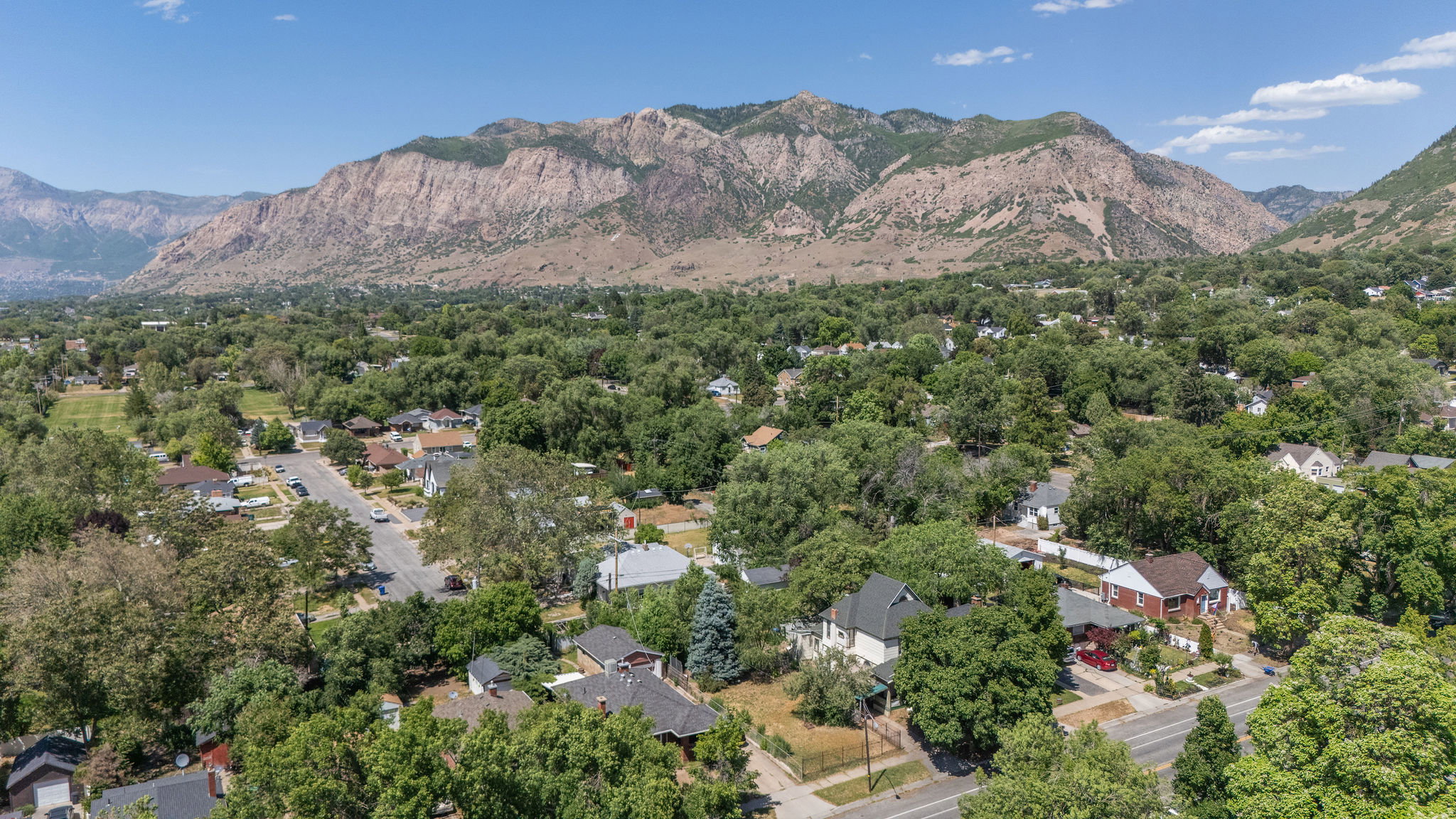Expansive mountain backdrop framing a tree-lined residential area with varied architectural styles