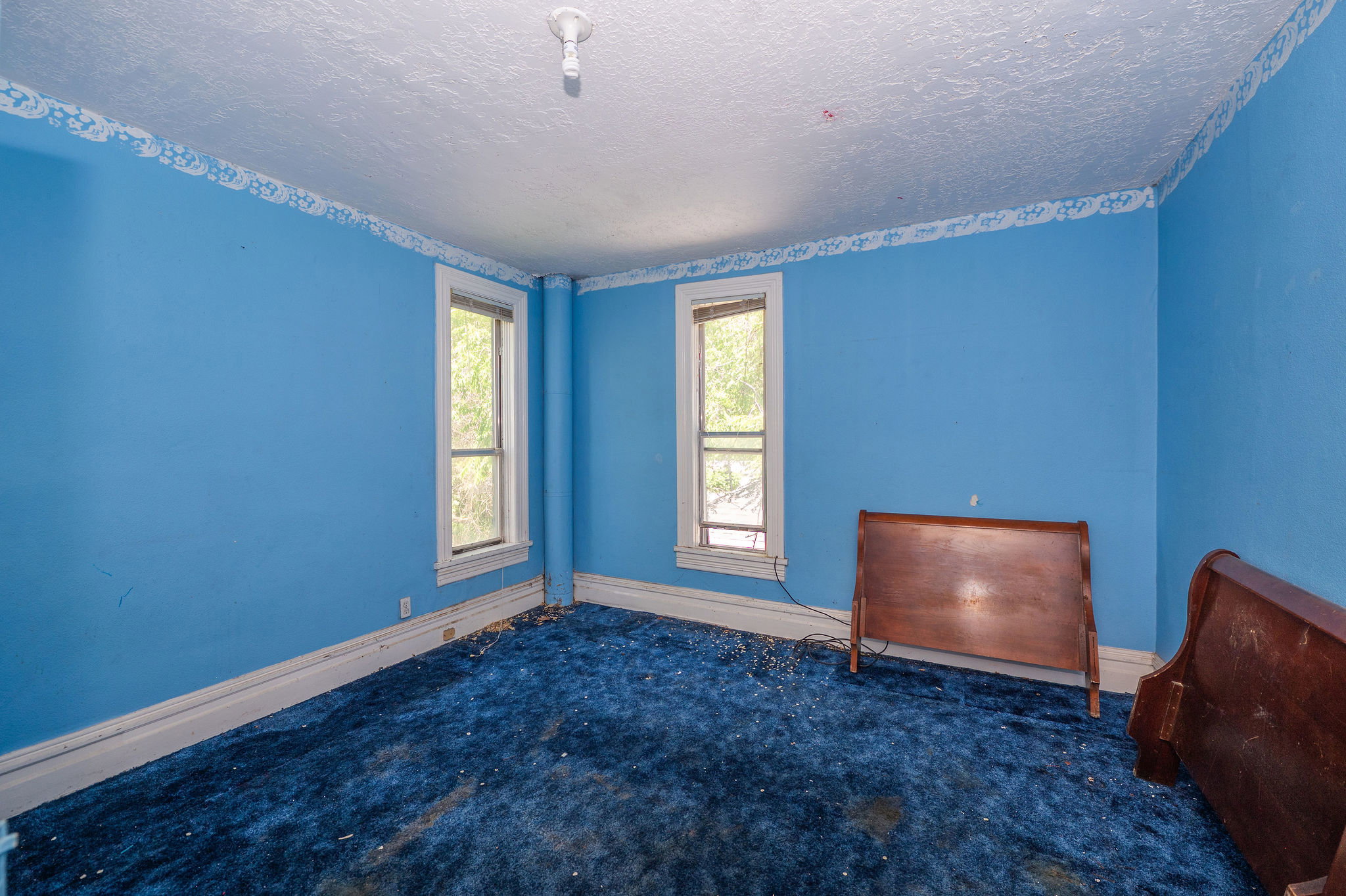 Room with two windows, a ceiling light fixture, and crown molding