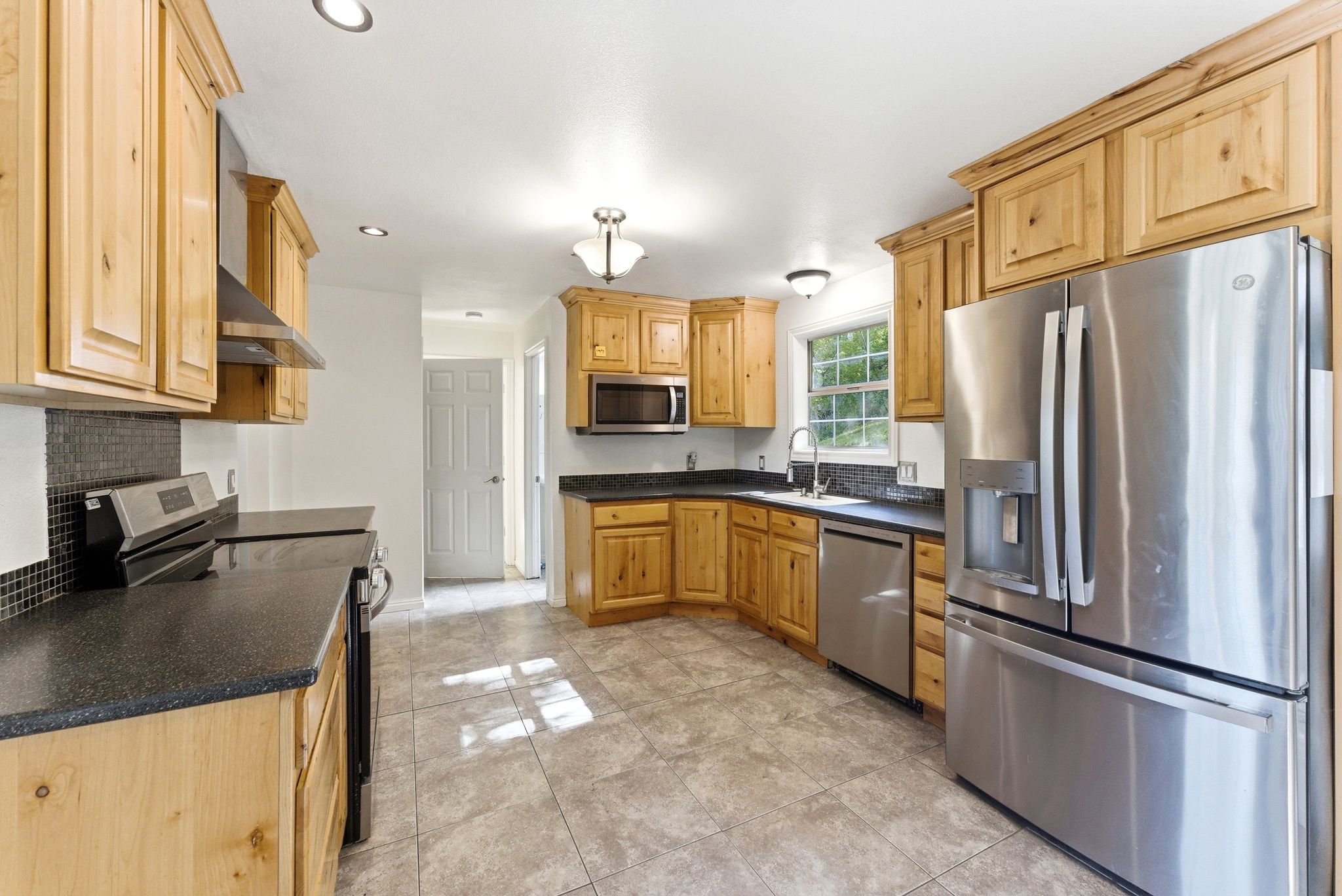 Kitchen featuring Alder wood cabinetry and tile floors. Stainless refrigerator included