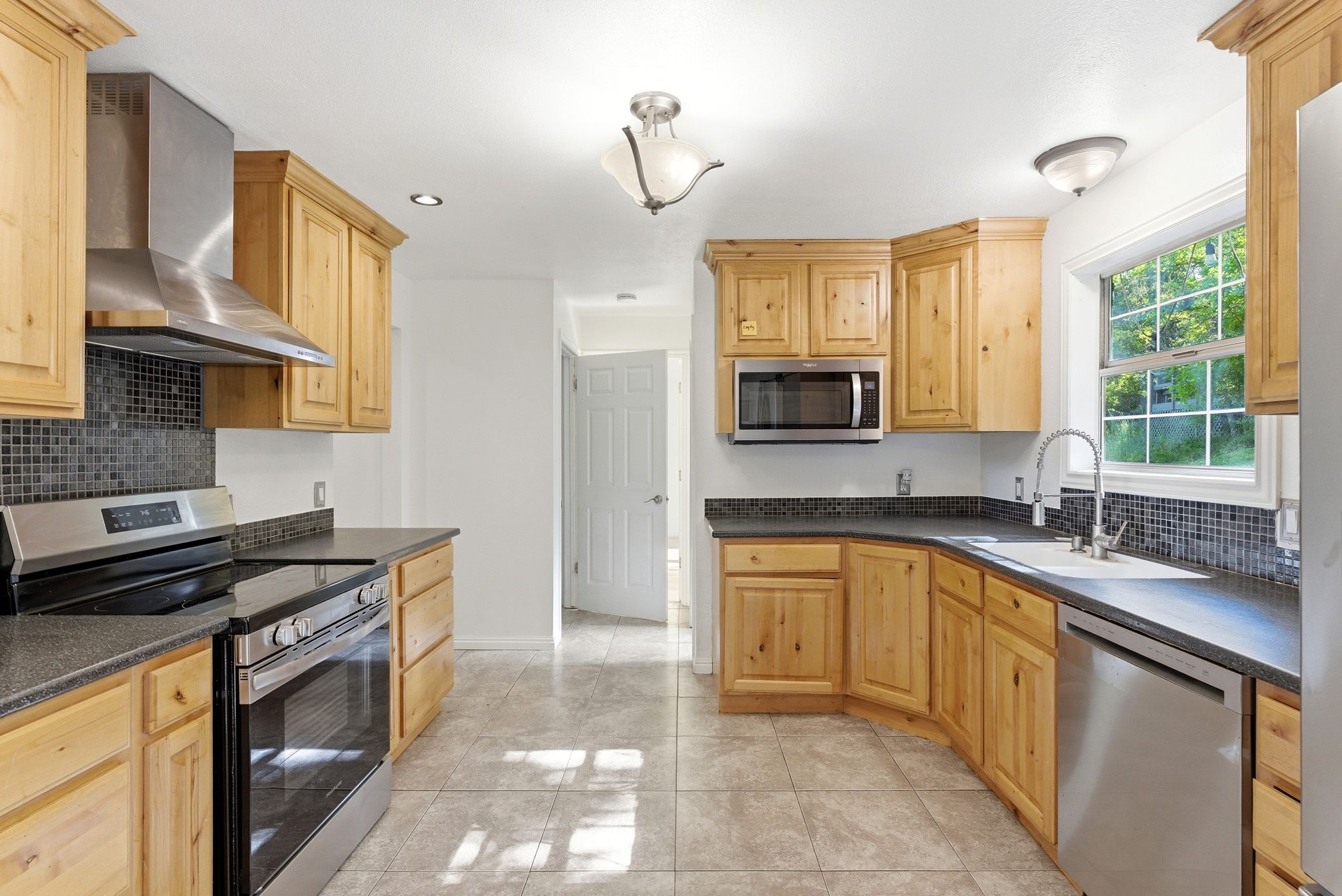 Kitchen featuring Alder cabinets, stainless steel appliances and tile floors