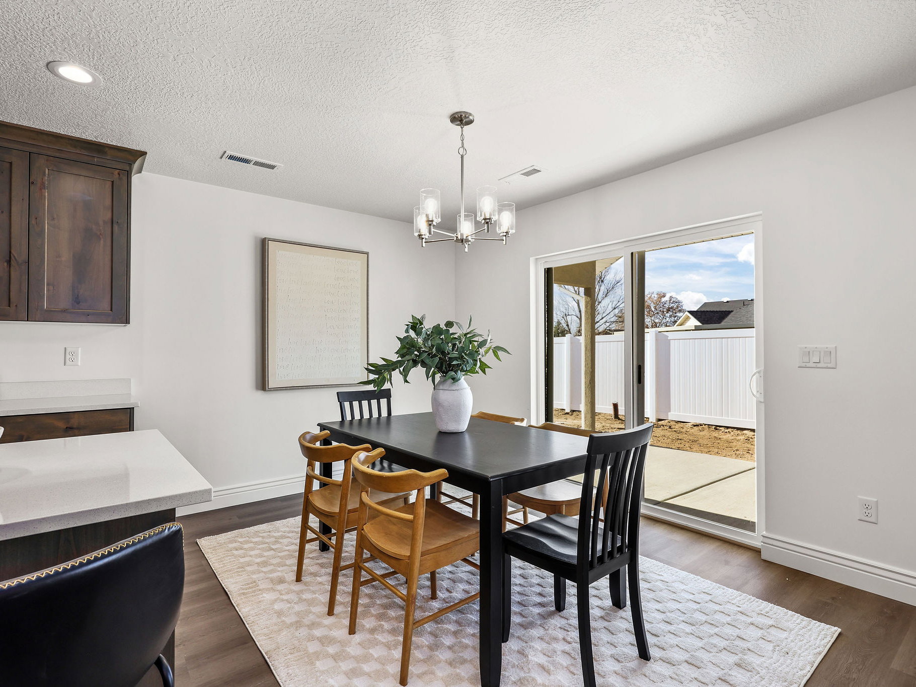 Dining area featuring wood-finish flooring, a contemporary chandelier, and a sliding glass door providing access to an outdoor patio