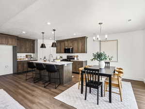Open-concept kitchen and dining area featuring wood-finish flooring, recessed lighting, and a kitchen island with pendant lighting