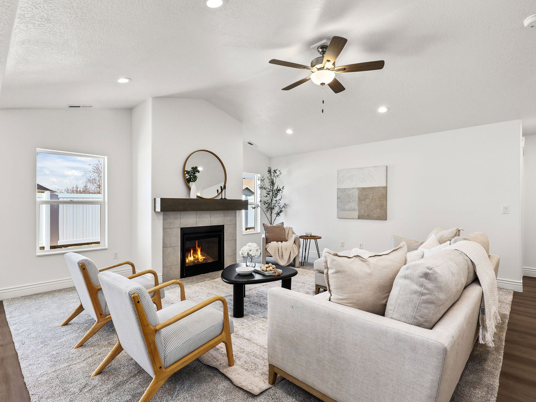 Vaulted ceiling living area featuring a fireplace with a tiled surround and wood mantel