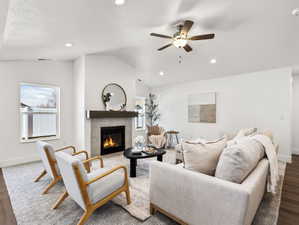 Vaulted ceiling living area featuring a fireplace with a tiled surround and wood mantel