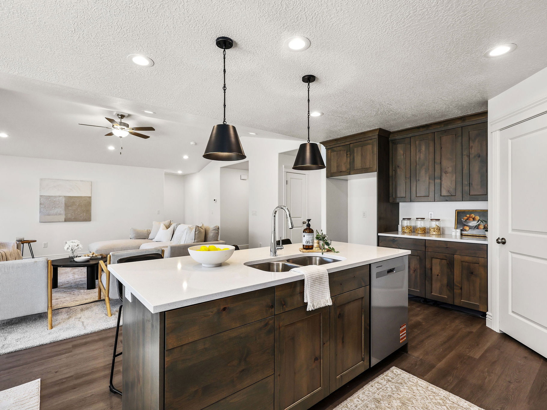 Kitchen island featuring a stainless steel sink, contemporary pendant lighting, and a white countertop