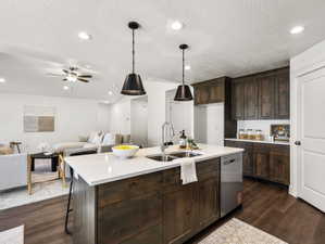 Kitchen island featuring a stainless steel sink, contemporary pendant lighting, and a white countertop