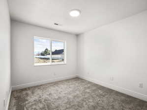Bright room featuring a large double-pane window, flush-mount ceiling light fixture, grey carpet, white walls, and layered baseboards