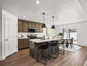 Kitchen featuring a center island with countertop seating, wood-finish flooring, stainless steel appliances, and wood cabinetry