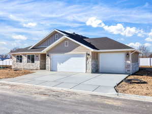 Contemporary-style residence featuring a two-car garage with white doors, light-toned horizontal siding, and stone veneer accents