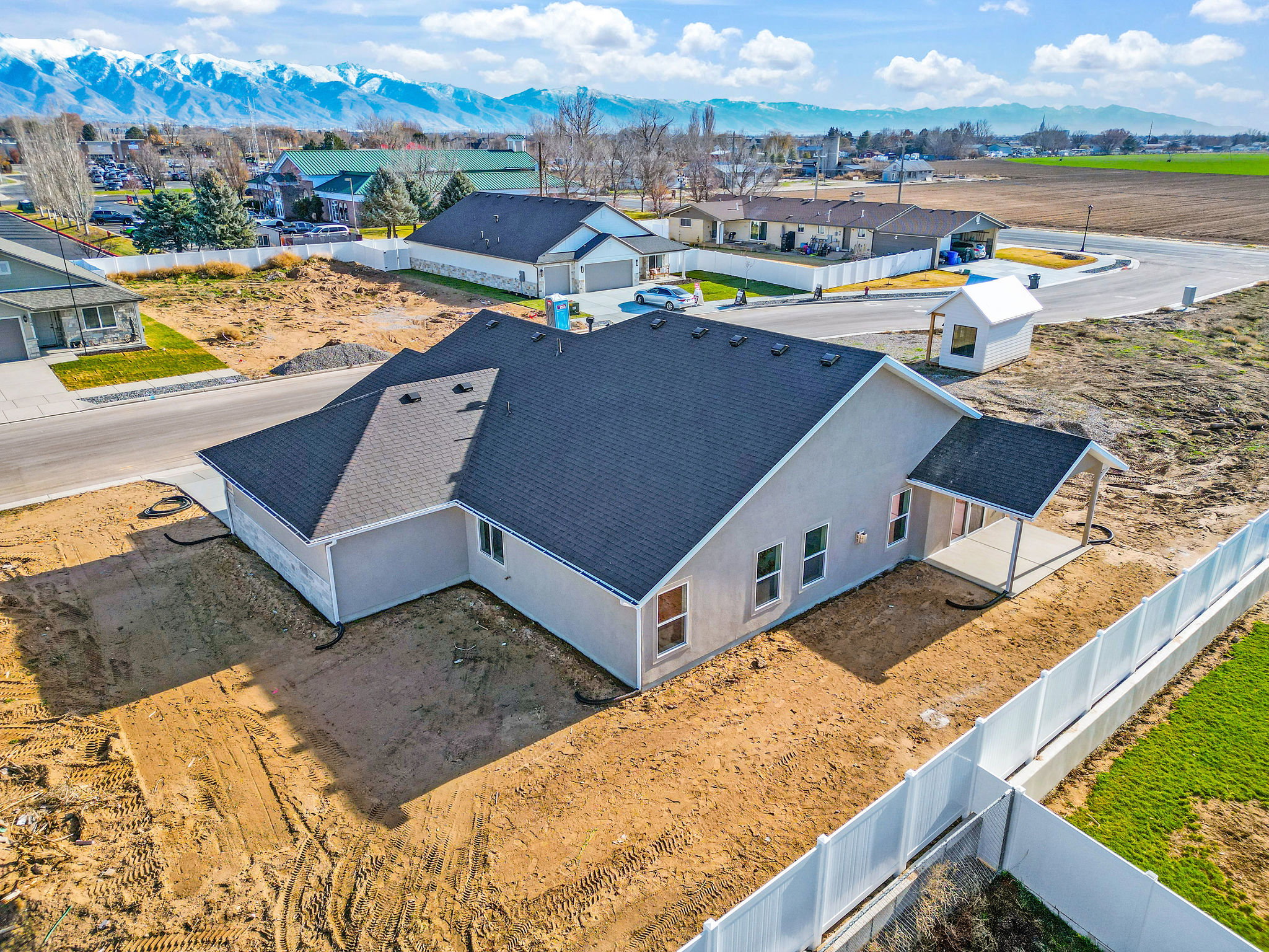 Newly constructed residence with a light-colored stucco exterior and dark-shingled roof