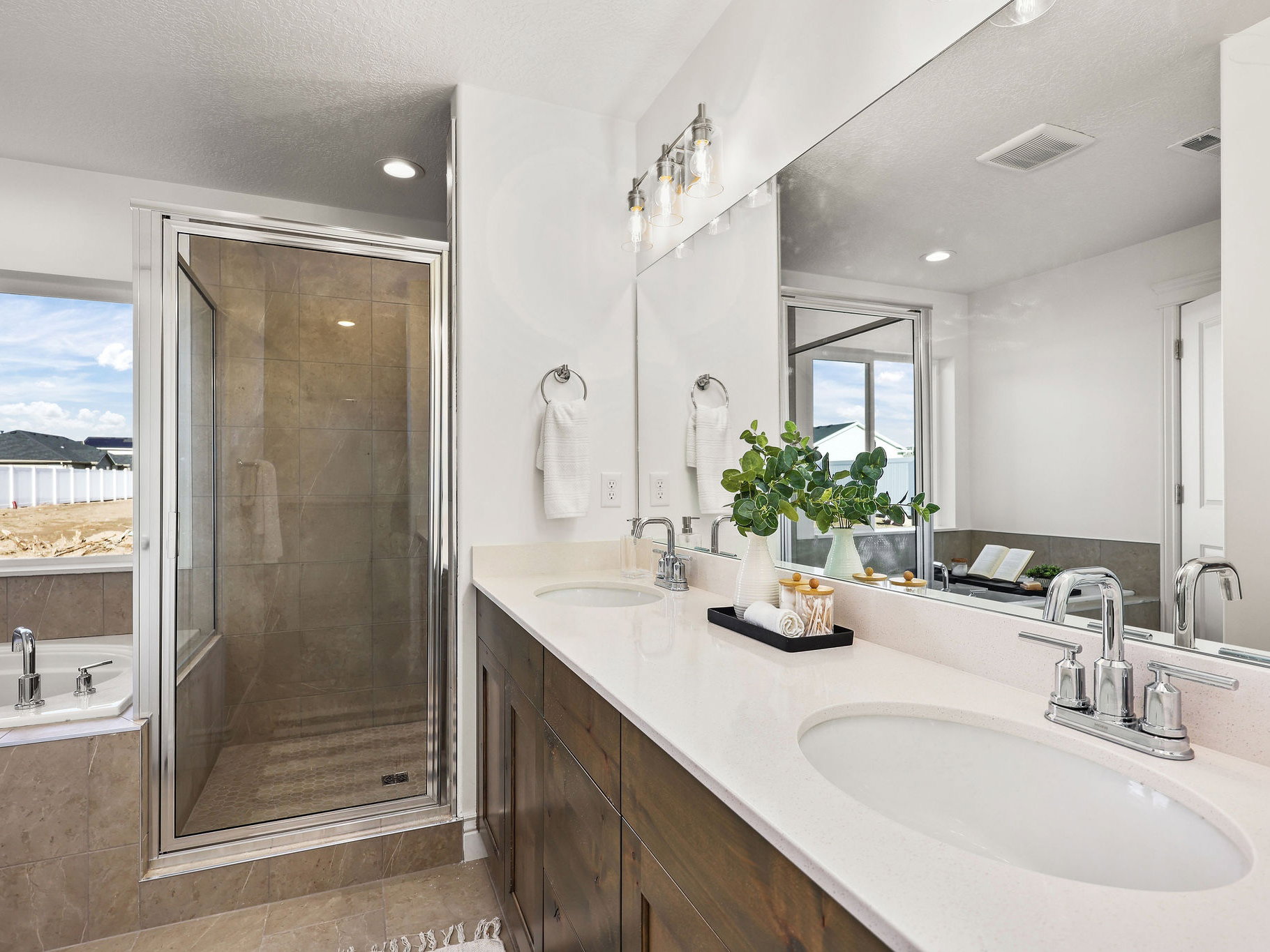 Spacious bathroom featuring a dual vanity with undermount sinks, chrome fixtures, and wood-finish cabinetry