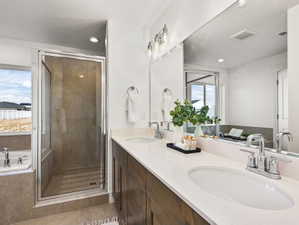 Spacious bathroom featuring a dual vanity with undermount sinks, chrome fixtures, and wood-finish cabinetry